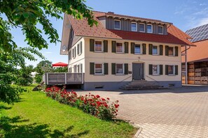 Ein zweistöckiges Gebäude mit rotem Ziegeldach, einem Hauseingang mit Stufen und einem gepflasterten Innenhof.