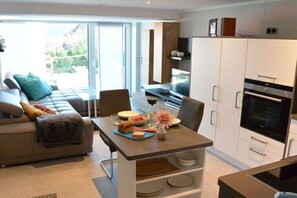 Ein modernes Wohnzimmer mit Sofa, Esstisch und Küchenzeile.