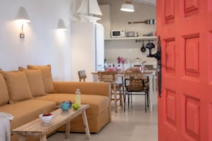 Ein Wohnzimmer mit einer Couch, einem Holztisch mit einer Schale und einer Flasche sowie einer roter Tür.