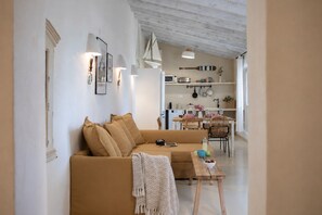 A living room with a sofa, a coffee table, and a dining area with a table and chairs. - Chalet Quinta la Sal 19 (Jávea)