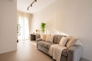 Ein modernes Wohnzimmer mit einer Couch, einem kleinen Beistelltisch und einem Blumentopf.