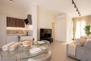 Ein stilvolles Wohnzimmer mit Glastisch, Sofa und Fernseher.