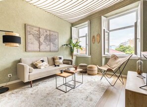 Ein Wohnzimmer mit einer Couch, einem Couchtisch, einem Sessel, einer Karte an der Wand und einem großen Fenster.