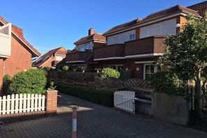 Eine Wohnstraße mit Backsteinhäusern, einem verschlossenen Eingang und strahlend blauem Himmel.