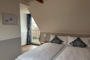 Ein Schlafzimmer mit einem großen Bett, einem Nachttisch, einer Lampe und einem Fenster mit Vorhängen.