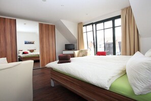Ein modernes Hotelzimmer mit einem großen Bett, einem Fernseher und Blick auf die Stadt.
