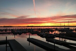 Un port de plaisance où des bateaux sont amarrés à des quais en bois, au coucher du soleil.