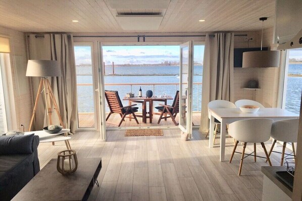 Ein modernes Interieur mit Essbereich, einer Couch und Blick auf das Wasser.