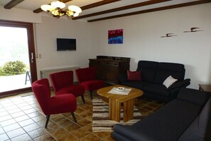 A living room with a sofa, chairs, a coffee table, a fireplace, and a TV mounted on the wall. - Holiday home in Piesport with barbecue (Piesport)