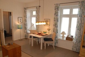 Ein Essbereich mit Tisch, Stühlen, einer Lampe und einem Fenster mit Vorhängen.