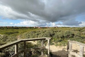 A wooden deck overlooking a grassy landscape with distant buildings. - Holiday apartment in Juist with swimming pool (Juist)