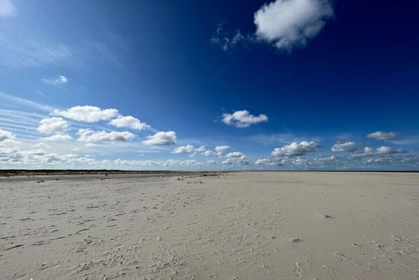 A vast, flat sandy beach with a clear sky and scattered clouds. - Holiday apartment in Juist with swimming pool (Juist)