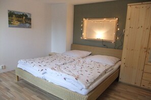 Ein Doppelbett mit floralem Überwurf, ein Nachttisch, eine Wandlampe und ein Gemälde an der Wand.