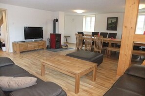 Ein Wohnzimmer mit Fernseher, Holzmöbeln, Kamin und Essbereich.