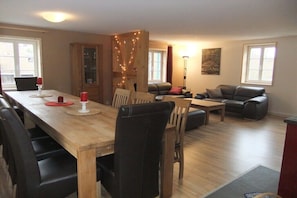 Ein Essbereich mit einem Holztisch und Stühlen, einer Couch und einer Lampe.