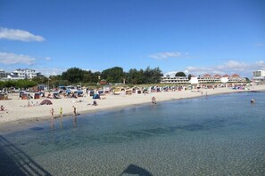 A beach with clear water, tents, and buildings in the background. - Holiday apartment with 2 bedrooms (Großenbrode)