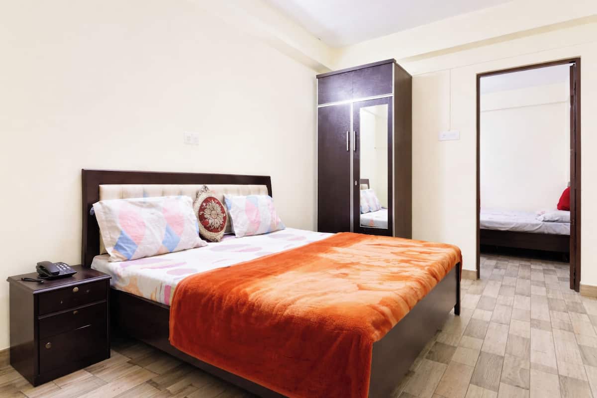 Un dormitorio con cama, mesita de noche, armario y espejo.