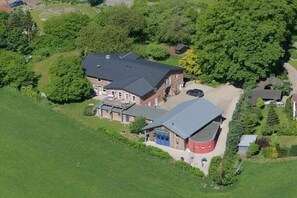 Eine Vogelperspektive eines großen, mehrstöckigen Hauses mit Garage, umgeben von üppigem Grün und Bäumen.