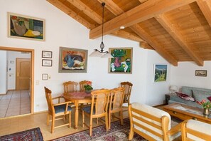 Ein Essbereich mit einem Holztisch und Stühlen, einer Pendelleuchte und Bildern an den Wänden.