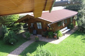 Ein Holzhaus mit rotem Dach, einem gepflasterten Weg und Kübelpflanzen.