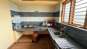 A kitchen with a gas stove, sink, and a water dispenser. - SOUPARNIKA LAKEVIEW HOMESTAY LLP (Wayanad)