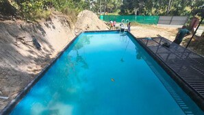 A rectangular swimming pool with a wooden deck surrounding it. - SOUPARNIKA LAKEVIEW HOMESTAY LLP (Wayanad)