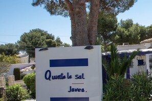 Ein Schild mit fremdsprachigem Text, umgeben von Bäumen und Gebäuden.