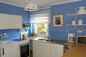 Eine kleine Küche mit Herd, Backofen, Spüle und Kaffeemaschine.