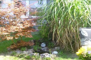 Un giardino con un piccolo stagno, rocce e diverse piante.