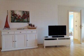 Ein Zimmer mit einem weißen Schrank, einem Flachbildfernseher auf einem Schrank und einem Gemälde an der Wand.