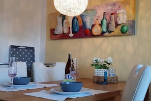 A dining table with a painting, a bottle, and a vase on it. - Holiday apartment with 1 bedroom (Königstein im Taunus)