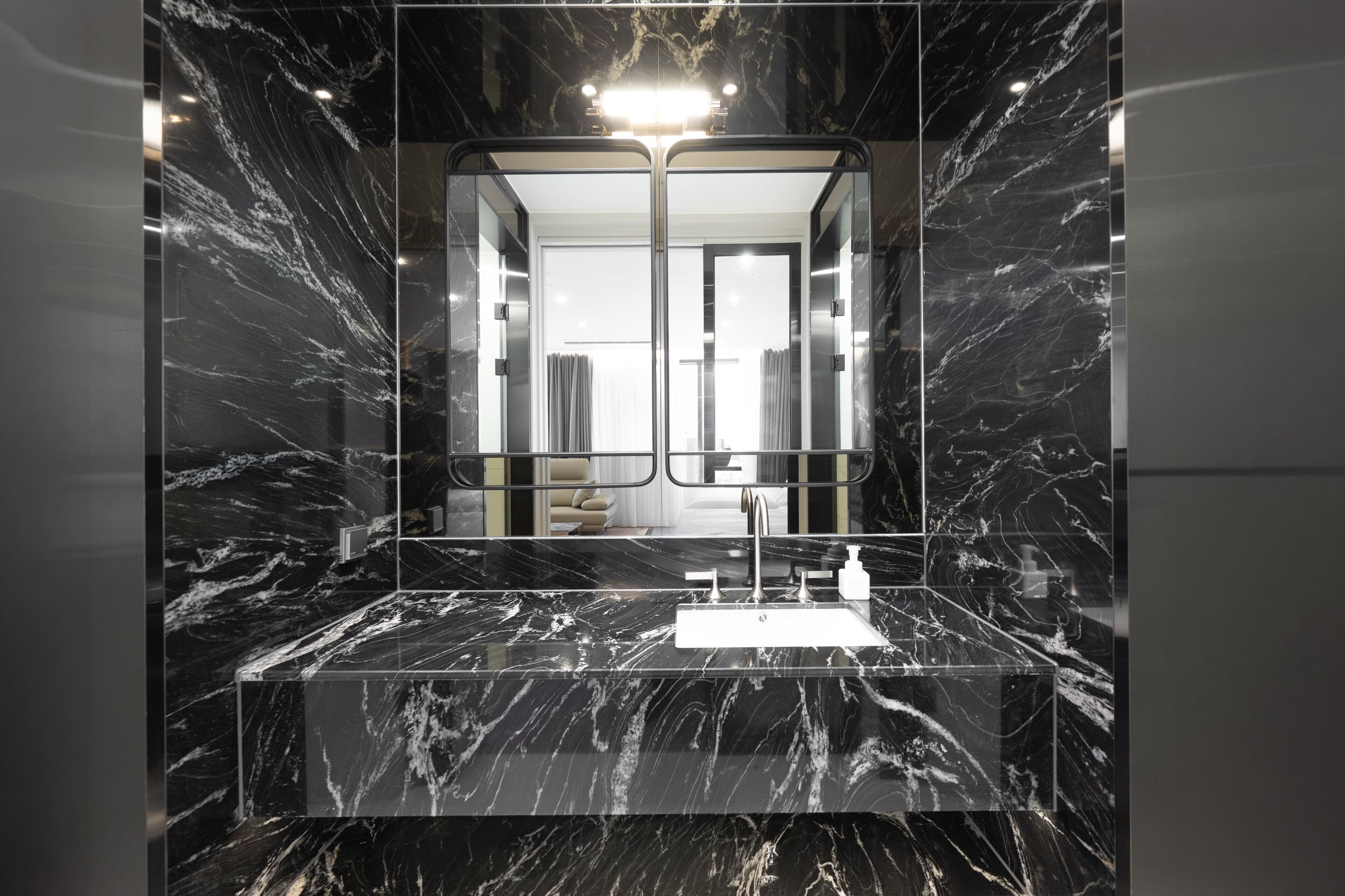 Une salle de bain moderne avec un meuble-lavabo en marbre, un grand miroir et une zone de douche bien visible.