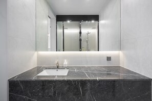 A modern bathroom with a marble sink, a glass shower enclosure, and a large mirror. - Pohang City Hotel (Pohang)