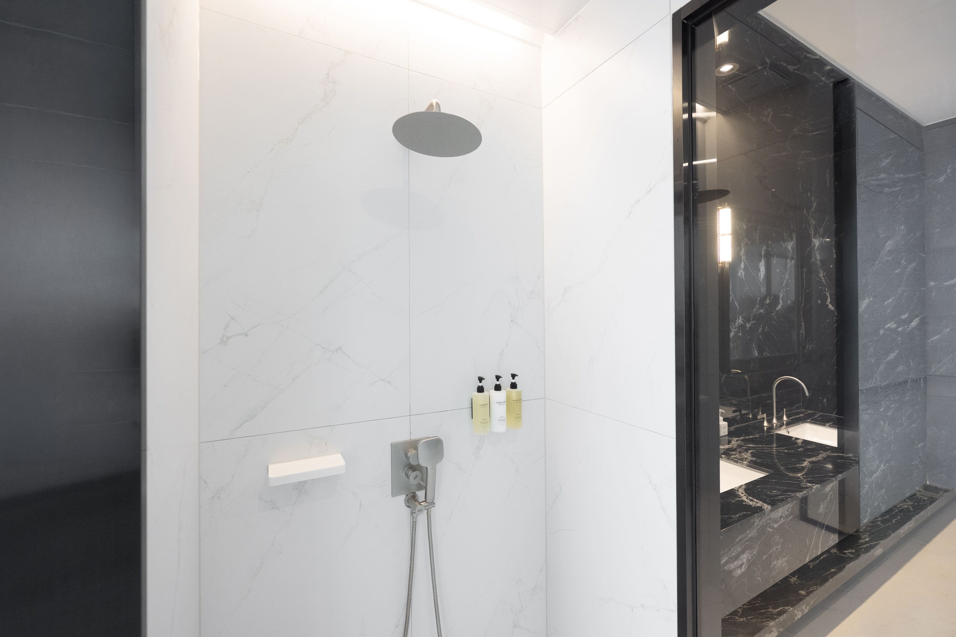 A modern bathroom with a shower, a sink, and a glass-enclosed shower area.