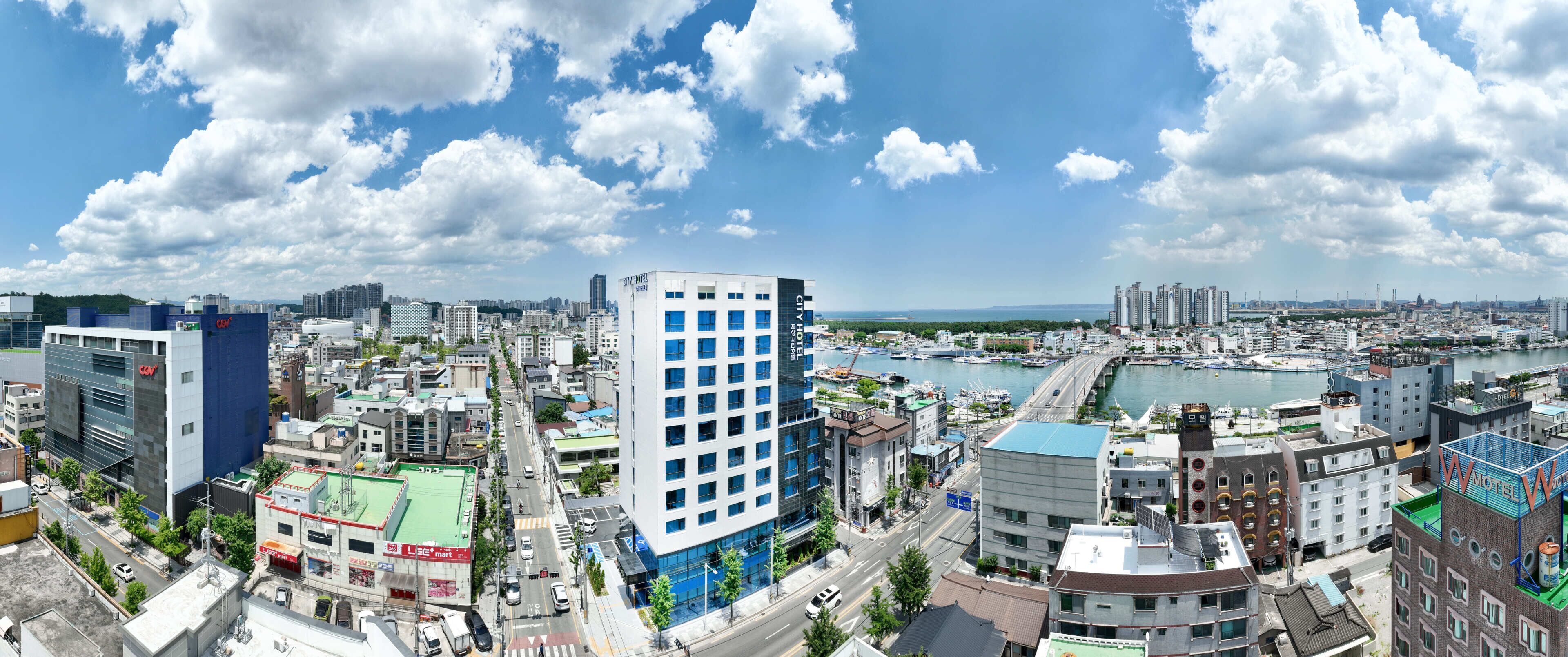 A cityscape with modern buildings, a marina, and a clear sky.