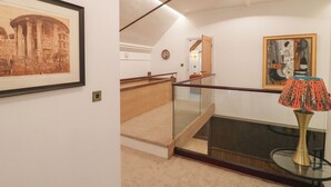 A staircase with glass railings, a framed picture of a historical building, and a modern lamp on a glass table. - Shrewsbury Lodge (Stafford)