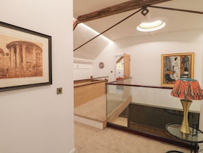 Eine Treppe mit Glastrennwand, ein gerahmtes Bild eines historischen Gebäudes und eine moderne Lampe auf einem Glastisch.
