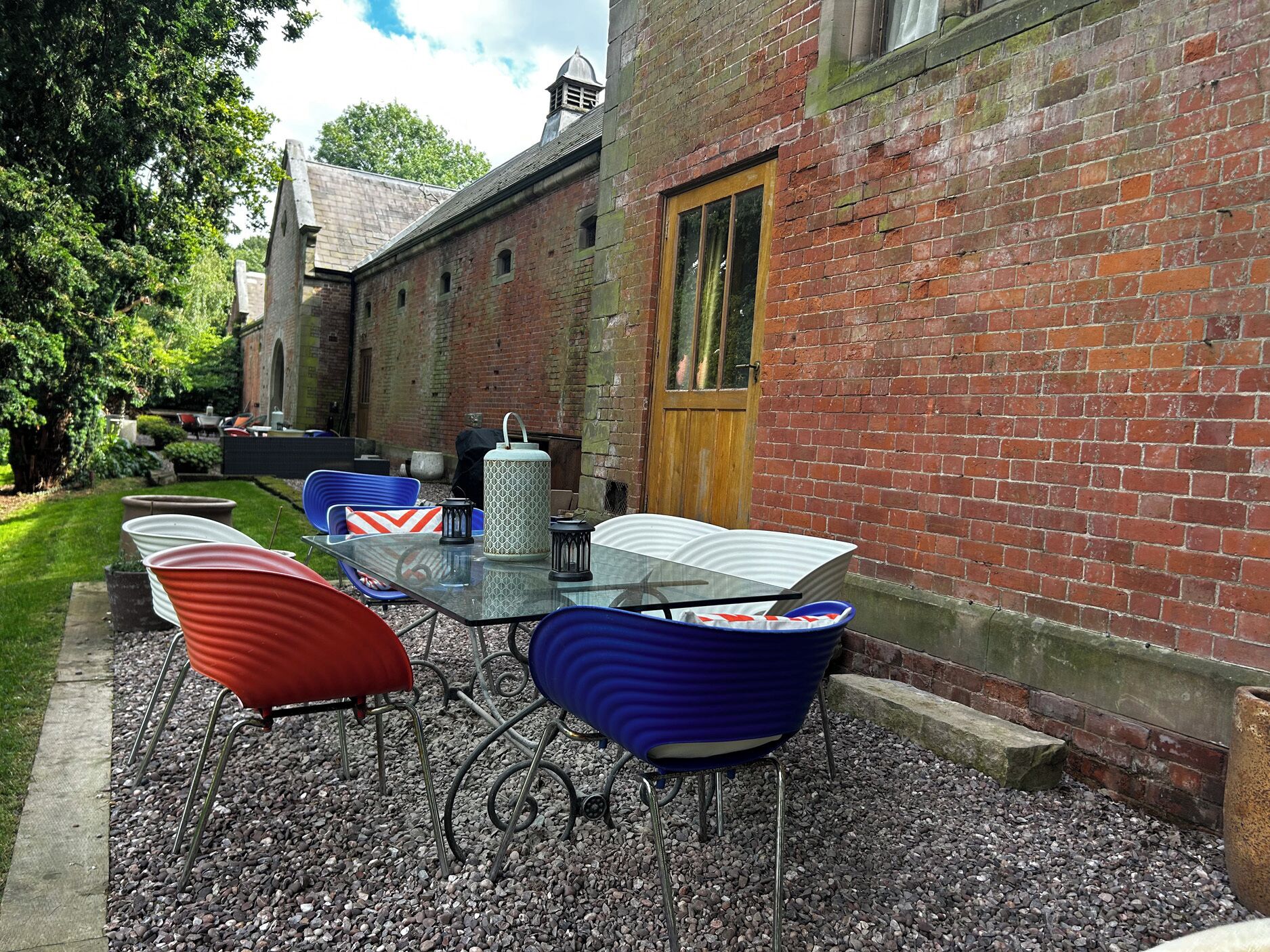 A patio with a table and chairs, a brick building, and a door.