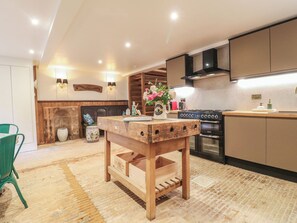A modern kitchen with a wooden table, a stove, and a sink.