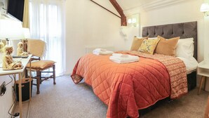 A bedroom with a bed, a desk with a computer, a chair, and a window with curtains. - Shrewsbury Lodge (Stafford)