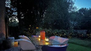 An outdoor seating area with a glass table, metal chairs, and decorative lanterns. - Shrewsbury Lodge (Stafford)