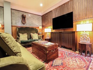 A living room with a sofa, a wooden chest, a television, and patterned carpet.