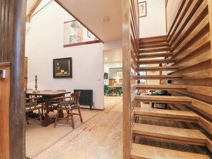 Una escalera con escalones de madera, un comedor con mesa y sillas, y un cuadro enmarcado en la pared.