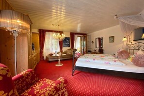 Ein Schlafzimmer mit einem Bett, einer Chandelüster, einer Couch und einem roten Teppich.