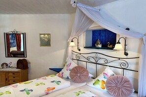 Een slaapkamer met hemelbed, nachtlampjes, een dressoir en een spiegel.