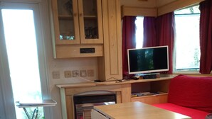 Living area - Mobile home on a quiet wooded lot with a barbecue and outdoor table. (Couret)