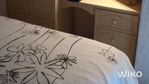 A bedroom with a bed, a nightstand, a mirror, and a wall-mounted shelf with towels. - Mobile home on a quiet wooded lot with a barbecue and outdoor table. (Couret)
