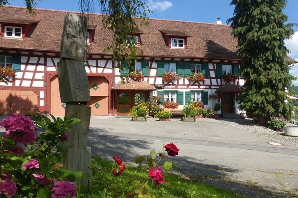 A traditional half-timbered building with a symmetrical facade, a central entrance, and flower boxes on the windowsills. - Apartment in Owingen with swimming pool (Owingen)
