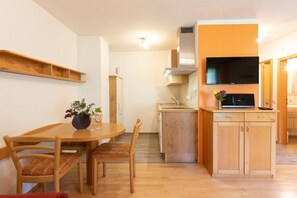 A compact kitchen with wooden cabinets, a built-in microwave, and a flat-screen TV mounted above the counter. - Apartment in Owingen with swimming pool (Owingen)