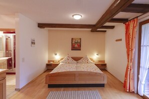 A bedroom with a wooden bed, two bedside tables, a nightstand, a painting on the wall, and a window with curtains. - Apartment in Owingen with swimming pool (Owingen)